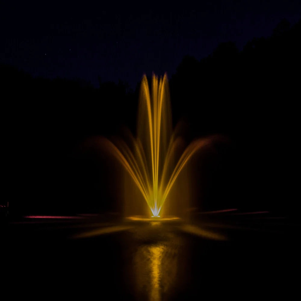 View of fountain in pond using the Bearon Aquatics Artemis Nozzle at night with yellow LED lights | Your Pond Pros 